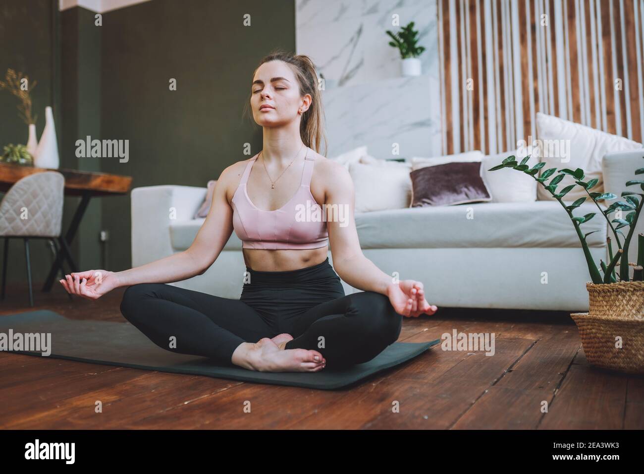 Attractive young woman sit in lotus yoga position at home in living ...