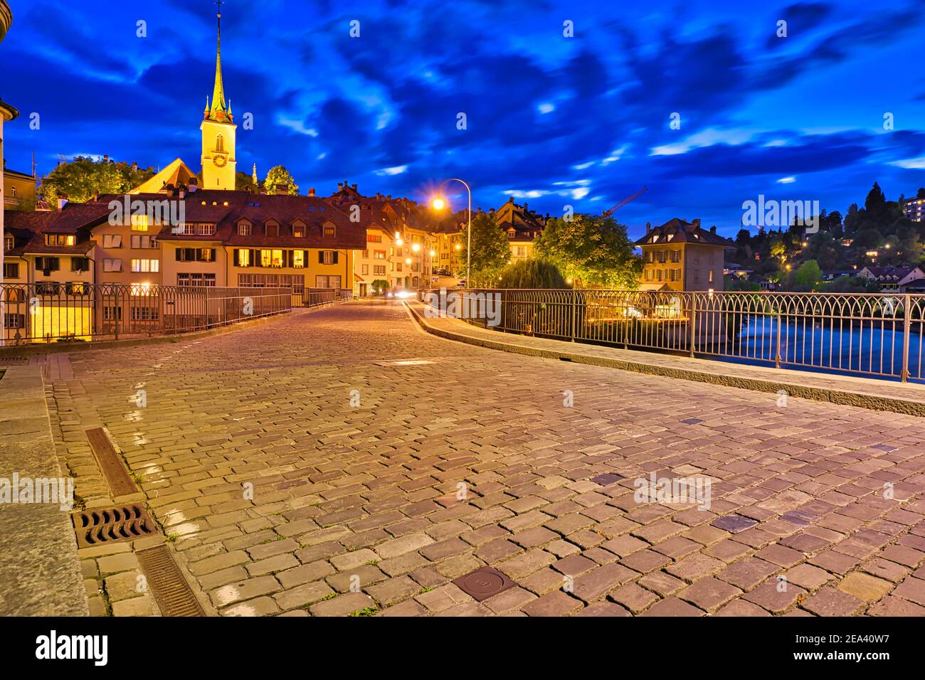 Pedestrian Untertorbrucke bridge in Bern old town with view of Nydeggkirche church illuminated at night. Capital of Switzerland, historic center Stock Photo