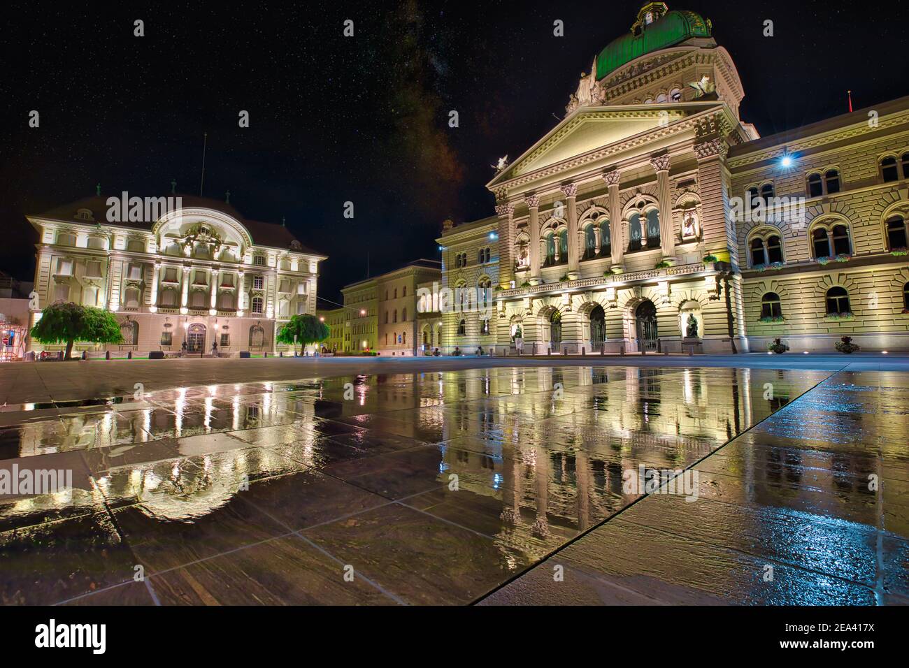 Federal Palace facade in Bern, Switzerland and Swiss National Bank illuminated at night. Swiss Parliament building reflecting in water in Bundesplatzn Stock Photo