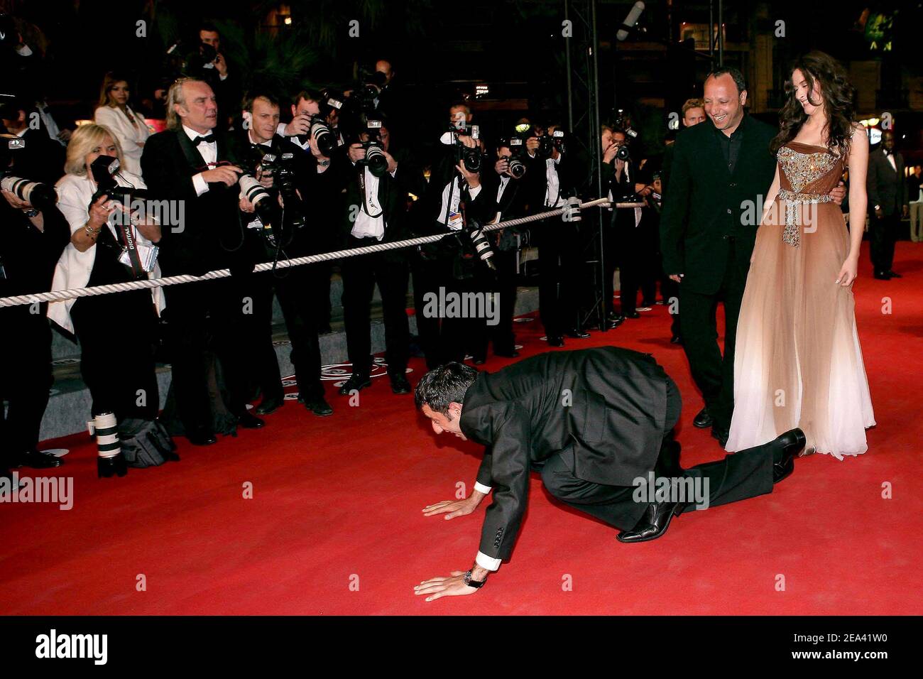 Turkish actor Nazim Kirik gives a kiss to the red carpet while Iraqi director Hiner Saleem and Turkish actress Belcim Bilgin are watching before the screening of their movie 'Kilometre Zero', during the 58th international Cannes film festival in Cannes, southern France, on May 12, 2005. Photo by Hahn-Nebinger-Klein/ABACA. Stock Photo