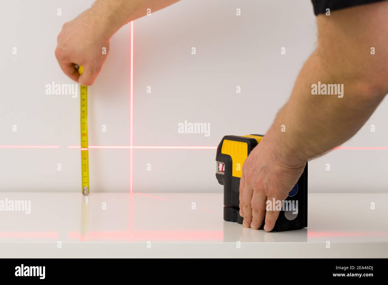 the worker marks right angles and lines during interior measurements Stock Photo