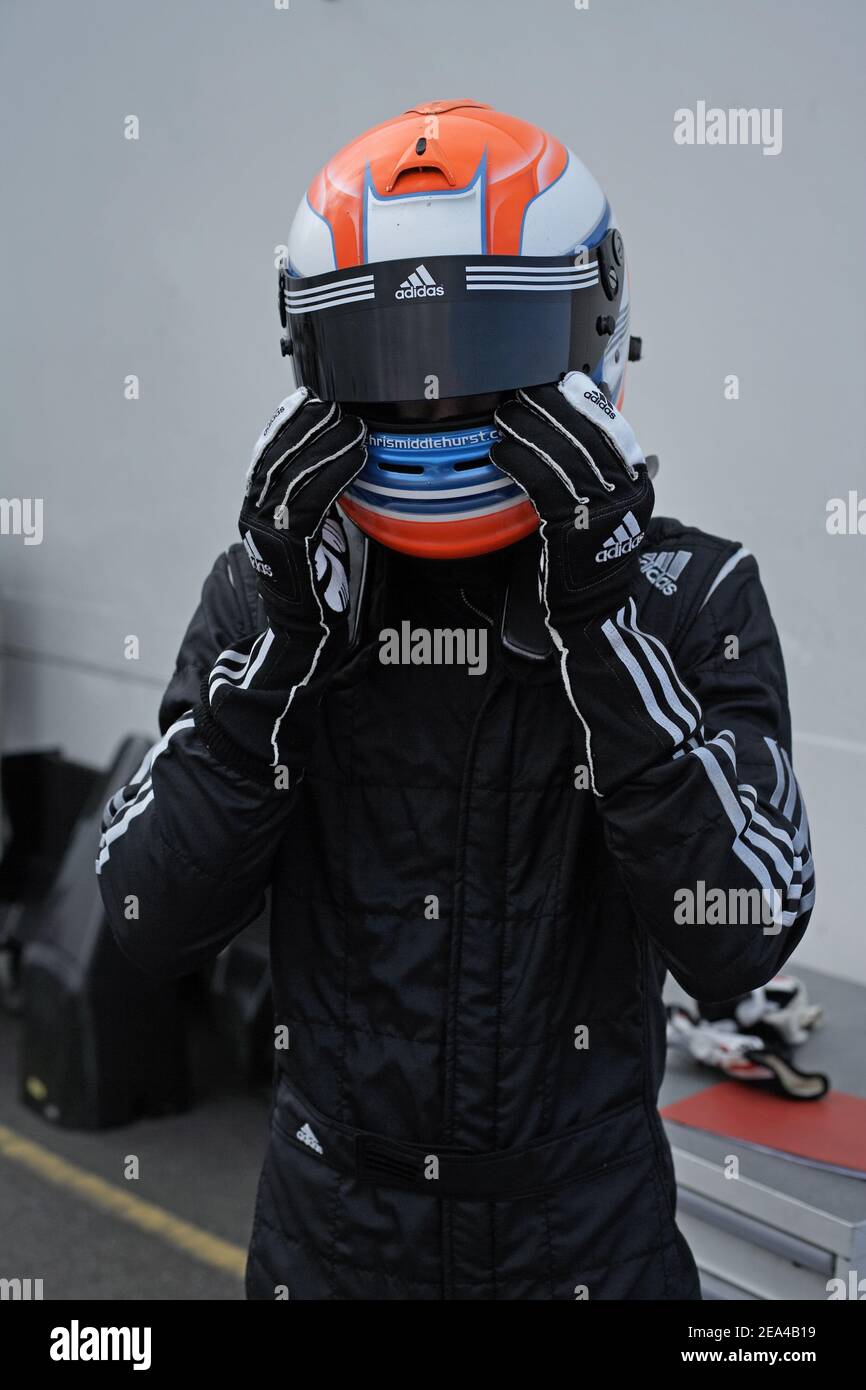 Young racing car driver in racing suiting and helmet. Young man with racing helmet. Racing driver wearing crash helmet standing. Stock Photo
