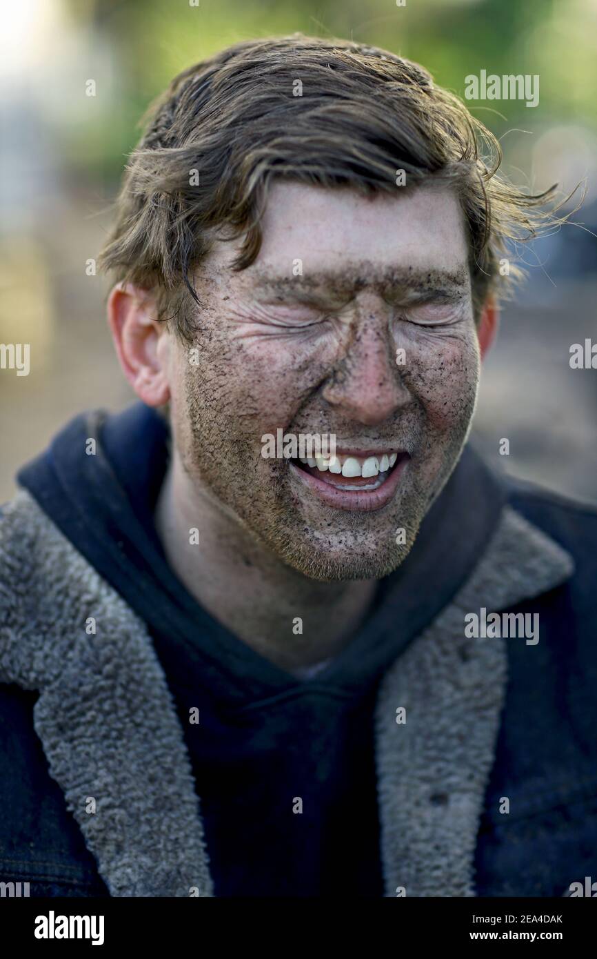 Close up of man covered by mud.A man's face covered in muddy spots after a bike session Stock