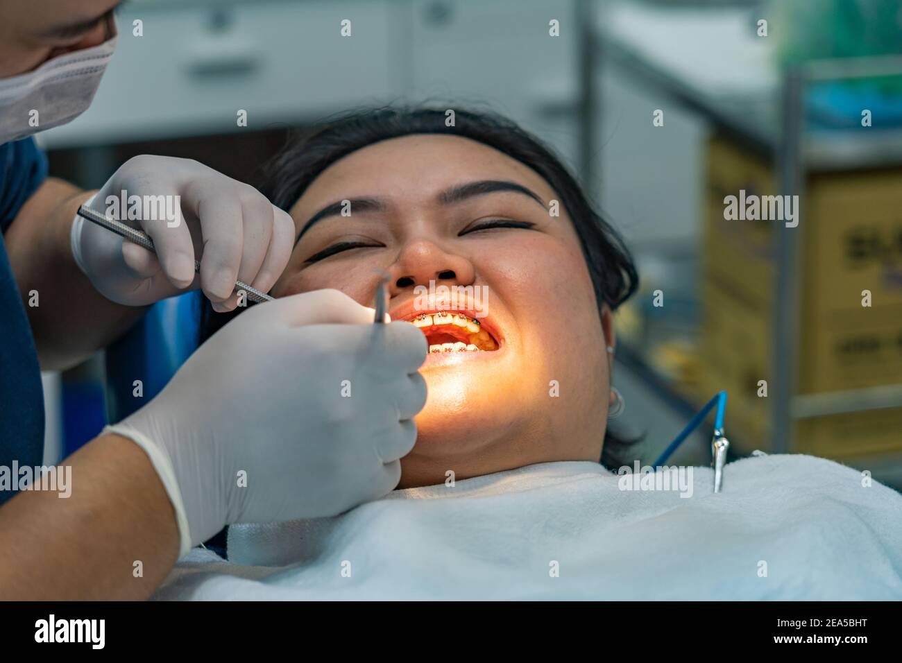 Close up photo of orthodontist checking teeth braces for woman in ...
