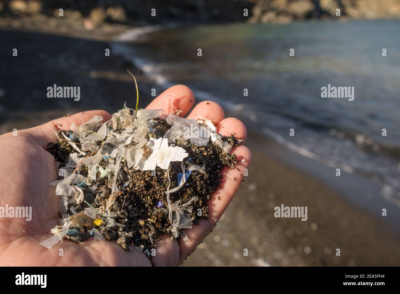 Small plastic parts and microplastics on the sand beach Stock Photo