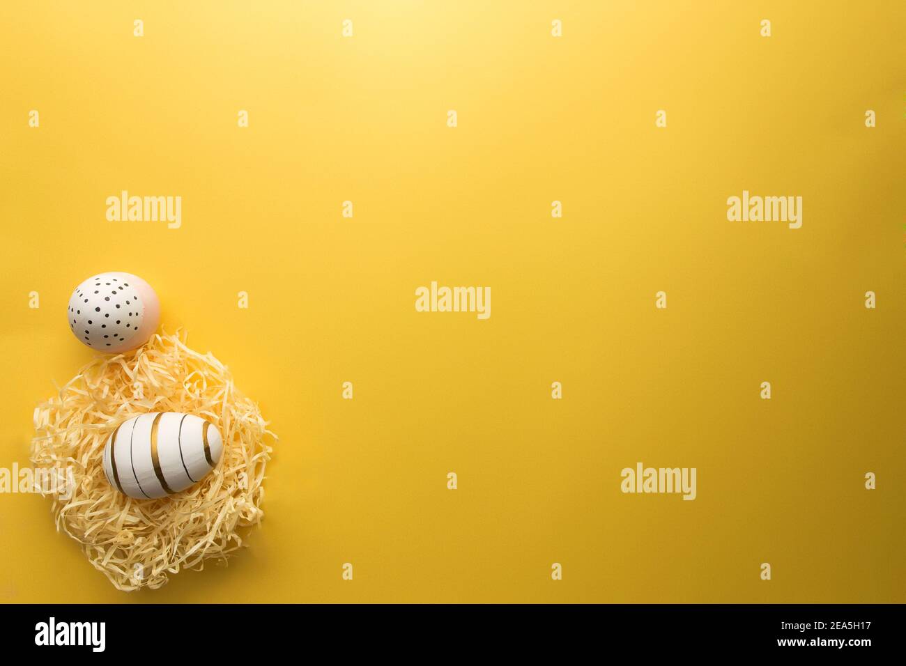 Colored Easter eggs in nest on yellow background Stock Photo