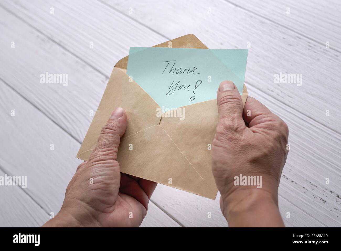 Man open and look at thank you card or note inside a brown envelope. Close up view. Stock Photo