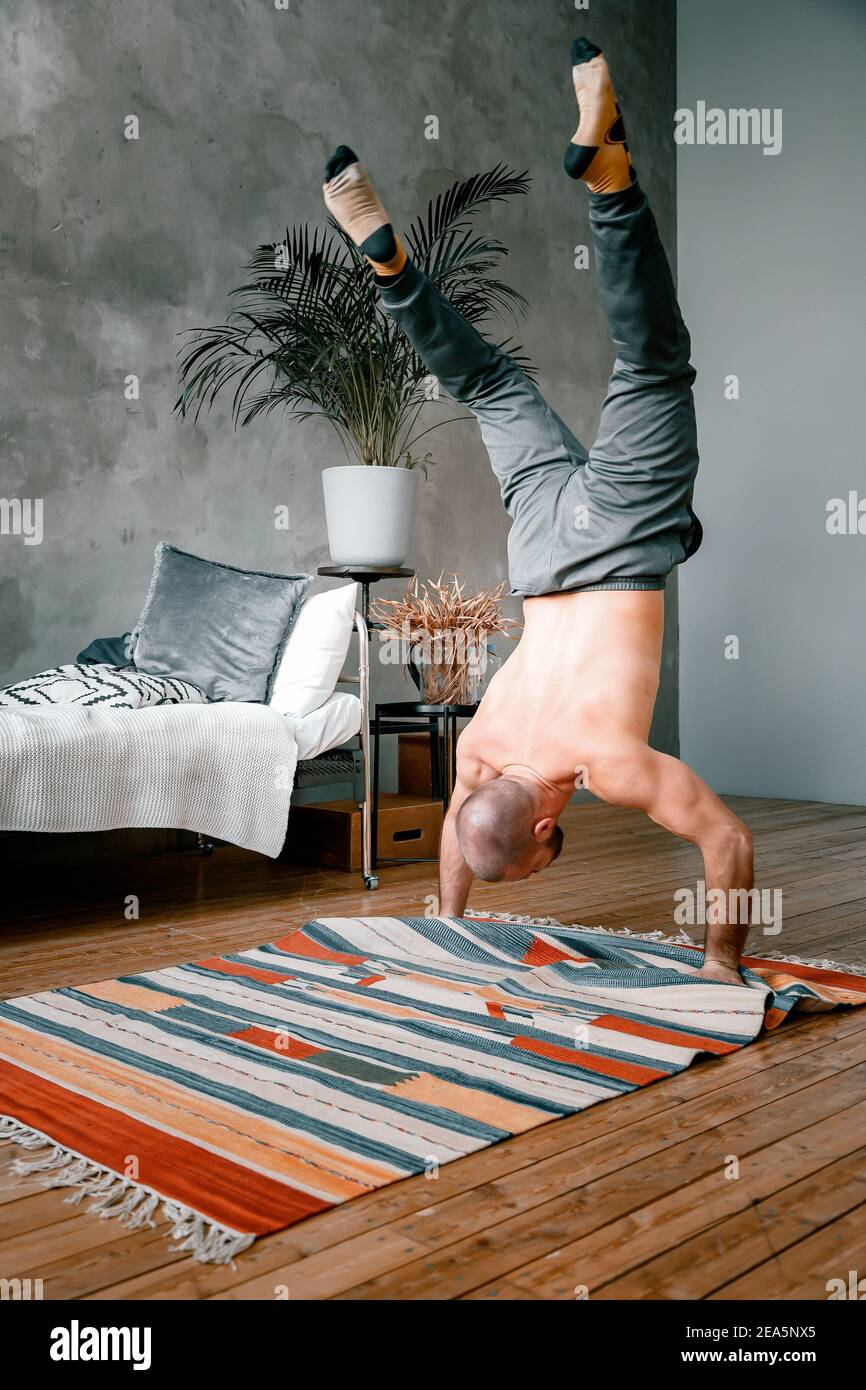 A athlete with black hair does acrobatics, walks on hands, does push-ups in  the bedroom, online training. The young man goes in for sports at home  Stock Photo - Alamy