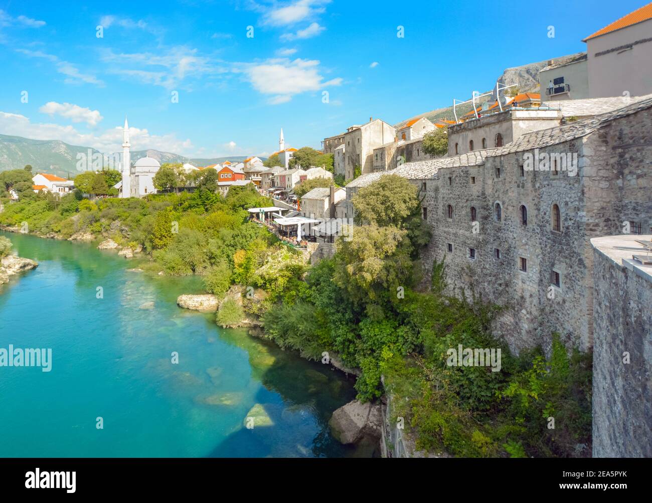 The river Neretva flows by the ancient wall surrounding the old town and village of Mostar, Bosnia and Herzegovina. Stock Photo