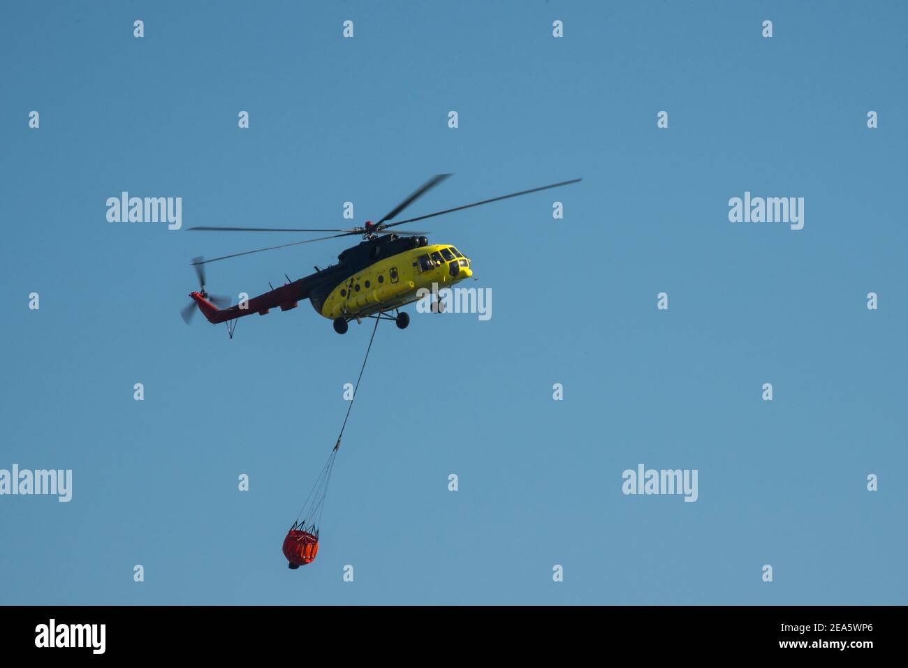Fire fighting helicopter with bucket against blue sky Stock Photo Alamy