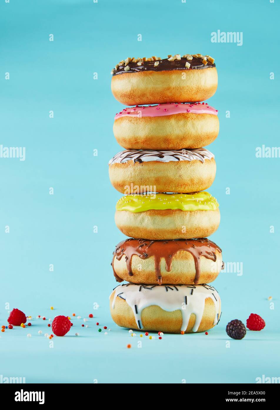 Multicolored donuts with icing and sprinkling stacked in a stack on a blue background. Stock Photo