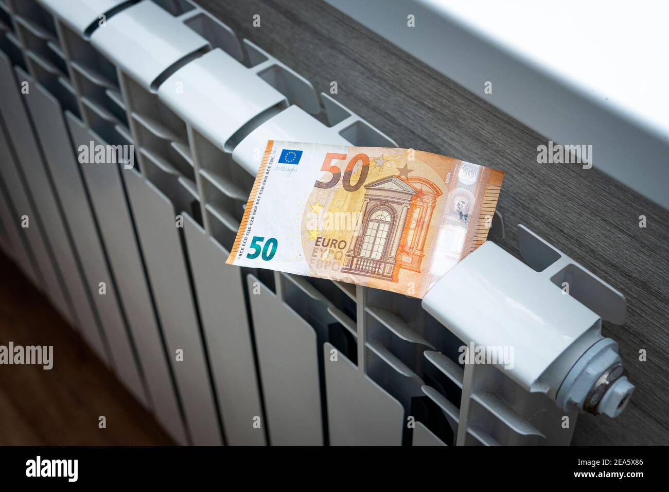 The concept of paying for heating in homes with a cold climate. Cash money is lying on a white metal radiator near the window. Stock Photo