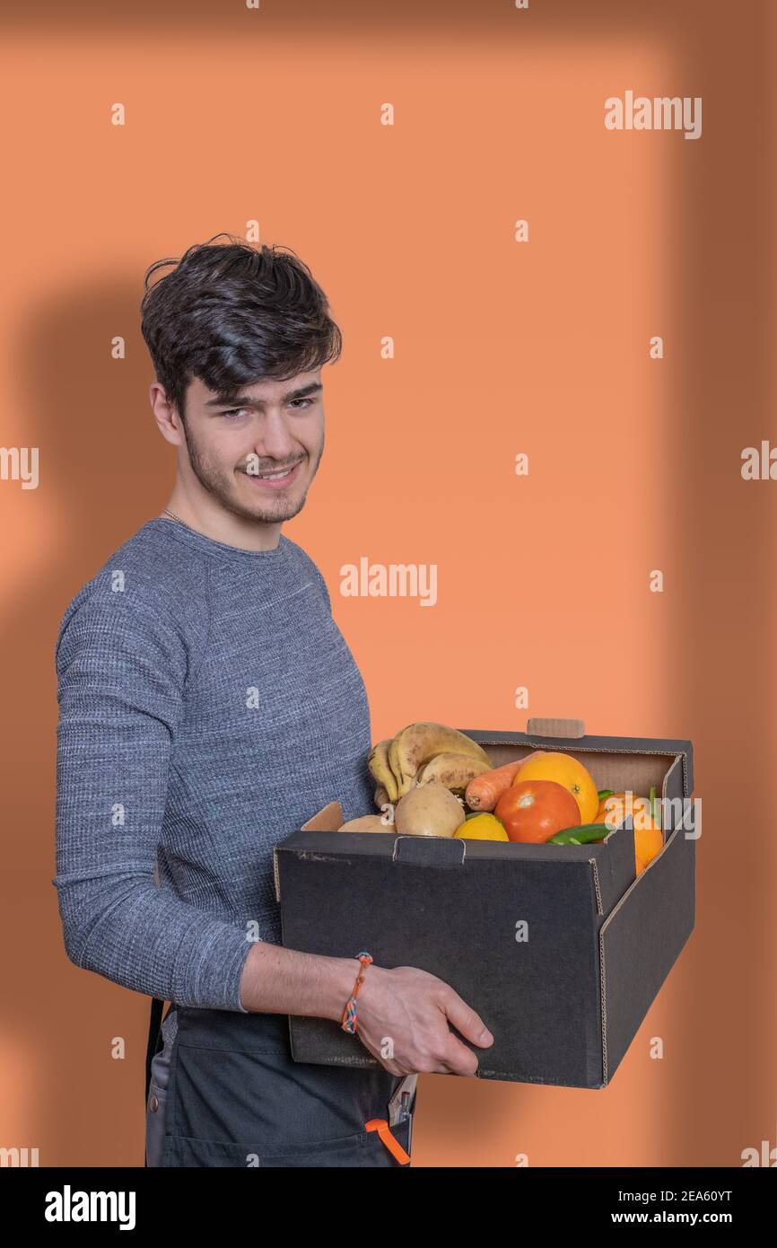 Delivery boy with fruit box in his hands delivering the order, dressed