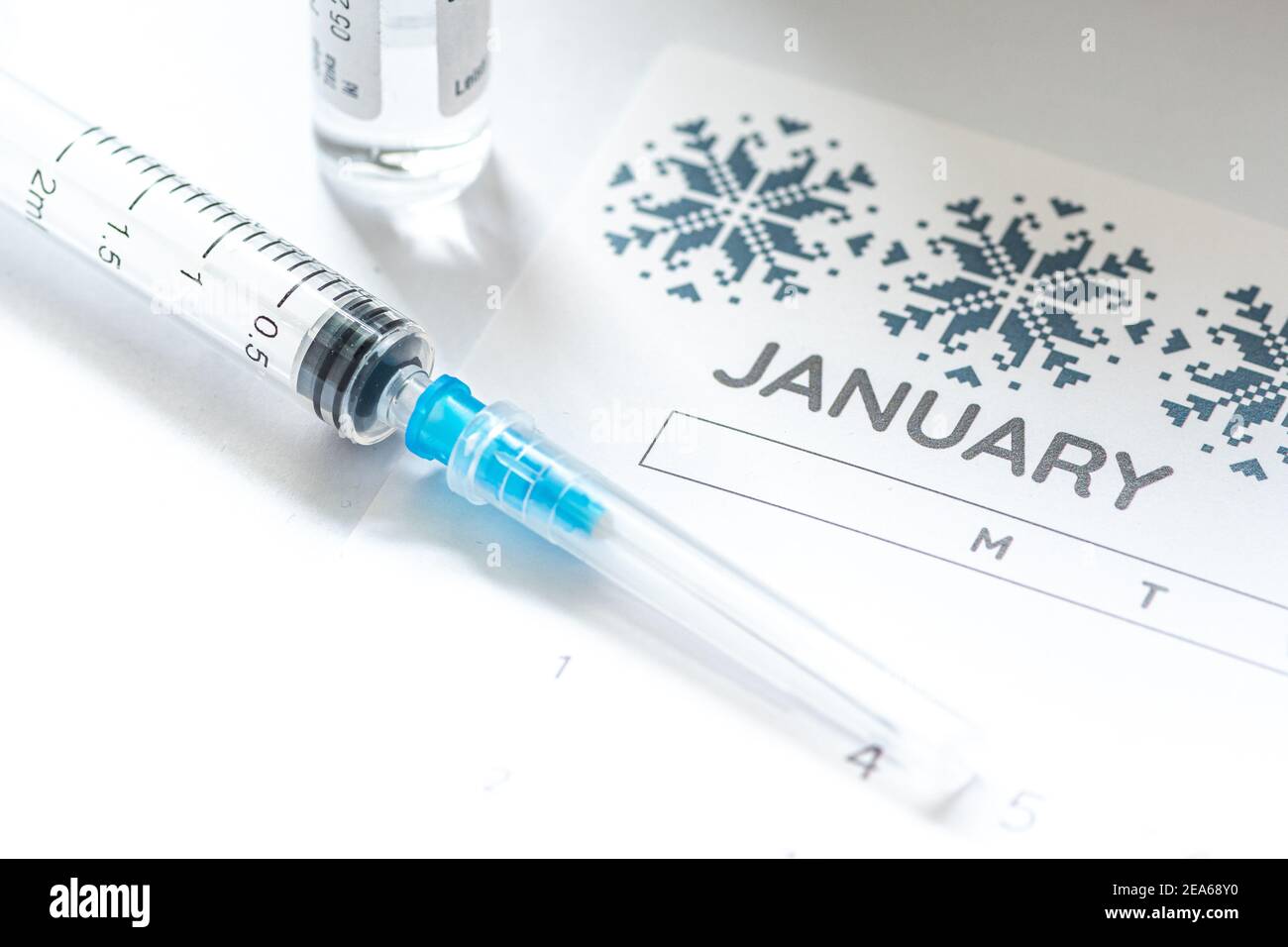 Syringe, glass vial or phial and calendar with month of January on a white table ready to be used. Covid or Coronavirus vaccine background, close up Stock Photo
