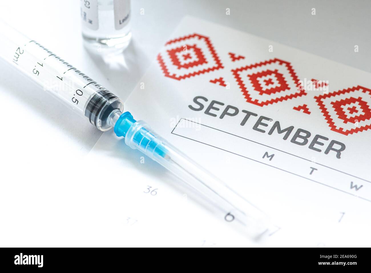 Syringe, glass vial or phial and calendar with month of September on a white table ready to be used. Covid or Coronavirus vaccine background, close up Stock Photo
