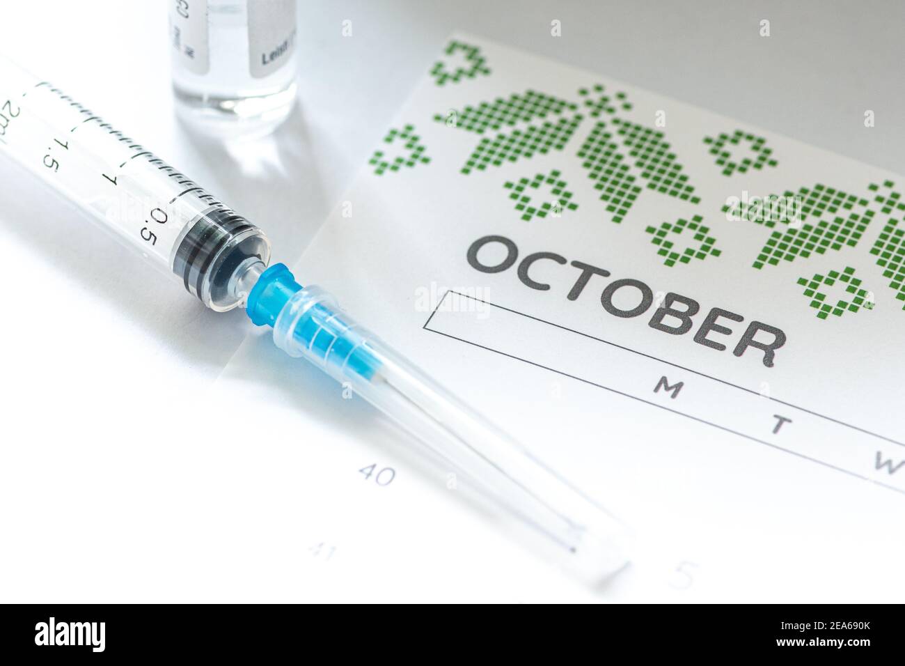 Syringe, glass vial or phial and calendar with month of October on a white table ready to be used. Covid or Coronavirus vaccine background, close up Stock Photo