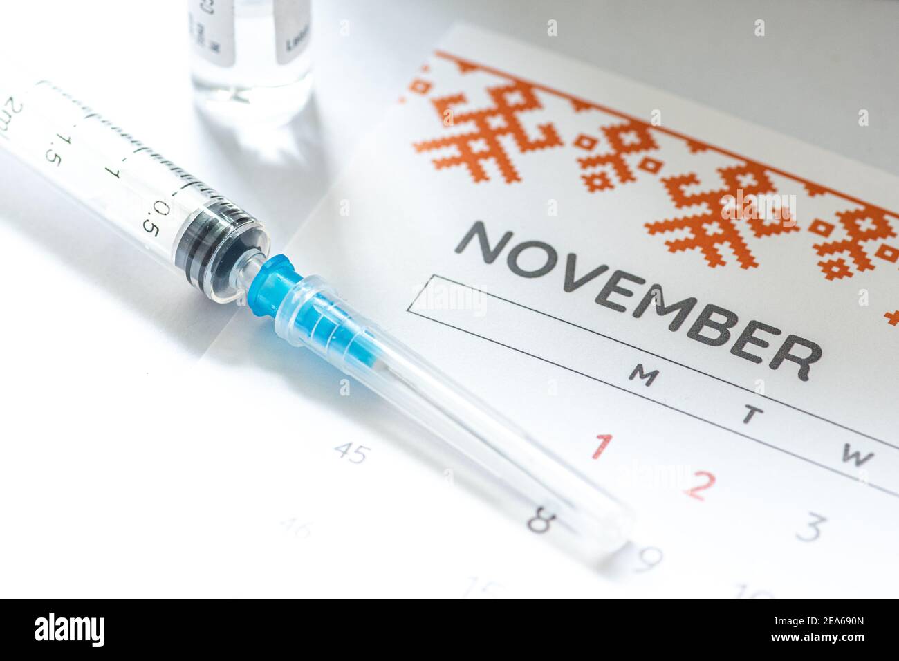 Syringe, glass vial or phial and calendar with month of November on a white table ready to be used. Covid or Coronavirus vaccine background, close up Stock Photo