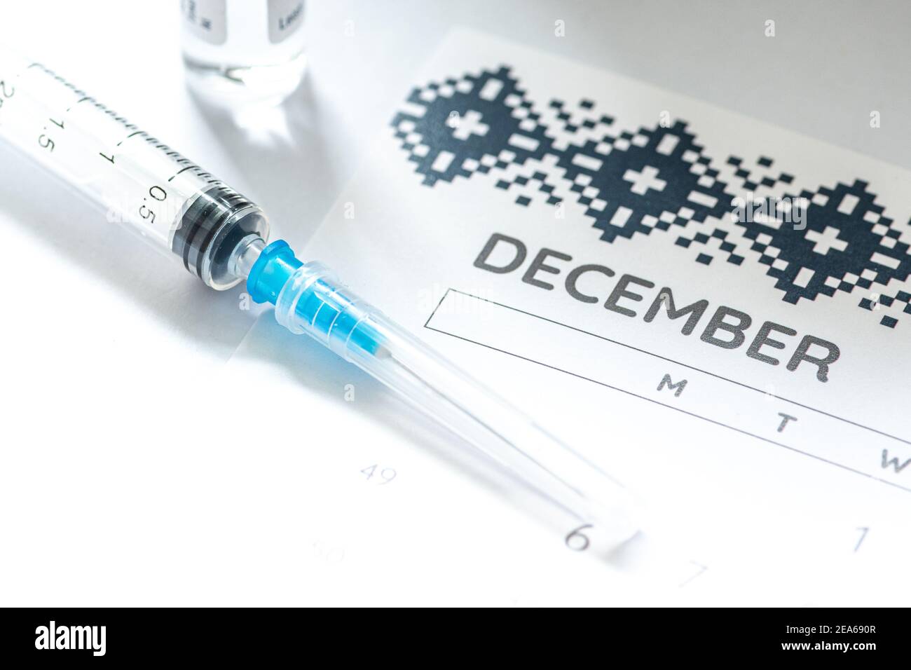 Syringe, glass vial or phial and calendar with month of December on a white table ready to be used. Covid or Coronavirus vaccine background, close up Stock Photo