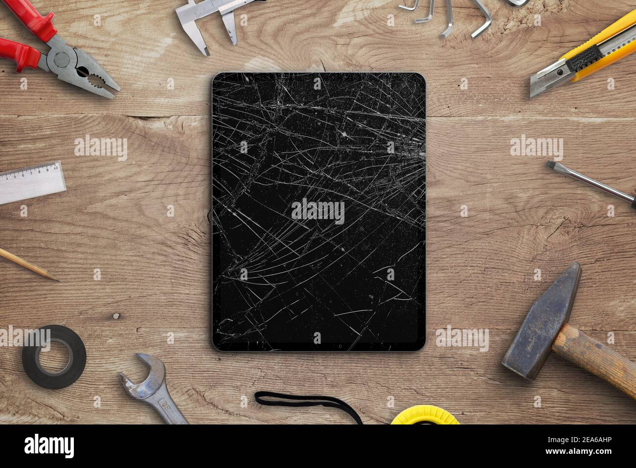 Repair broken tablet concept. Tablet with smashed disolay on work desk with tools beside. Top view, flat lay composition Stock Photo