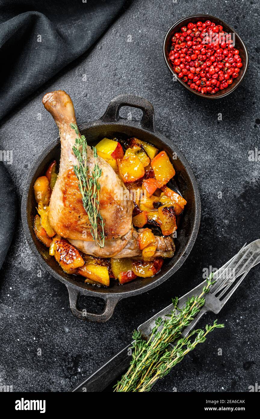 Oven-baked duck legs with figs and peachs. Black background. Top view
