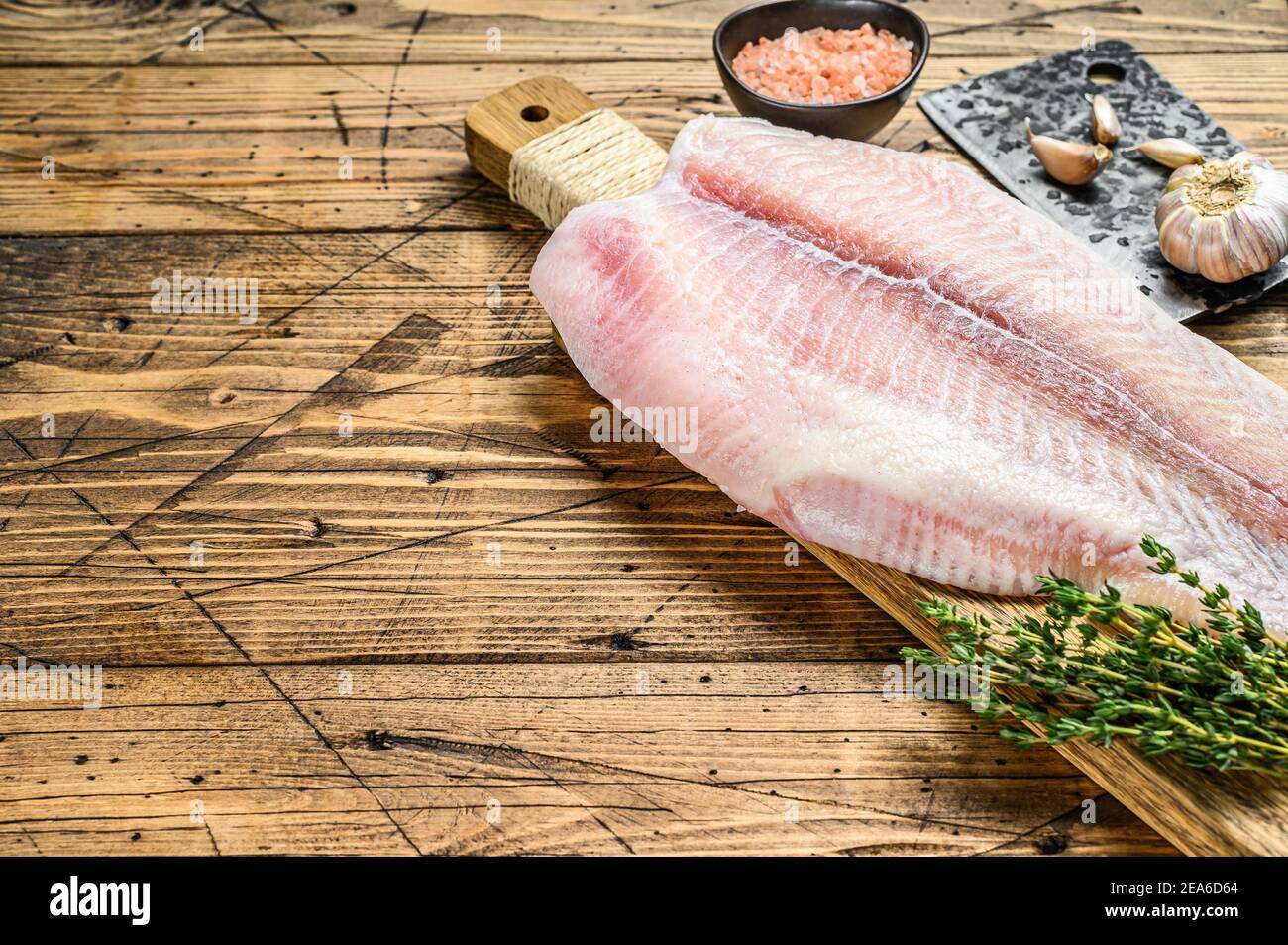 Raw fillet of pangasius fish on a cutting board. Wooden background. Top view. Copy space Stock Photo