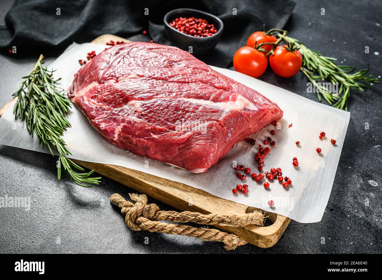 Raw brisket beef cut on a wooden cutting board. Black Angus beef. Black background. Top view
