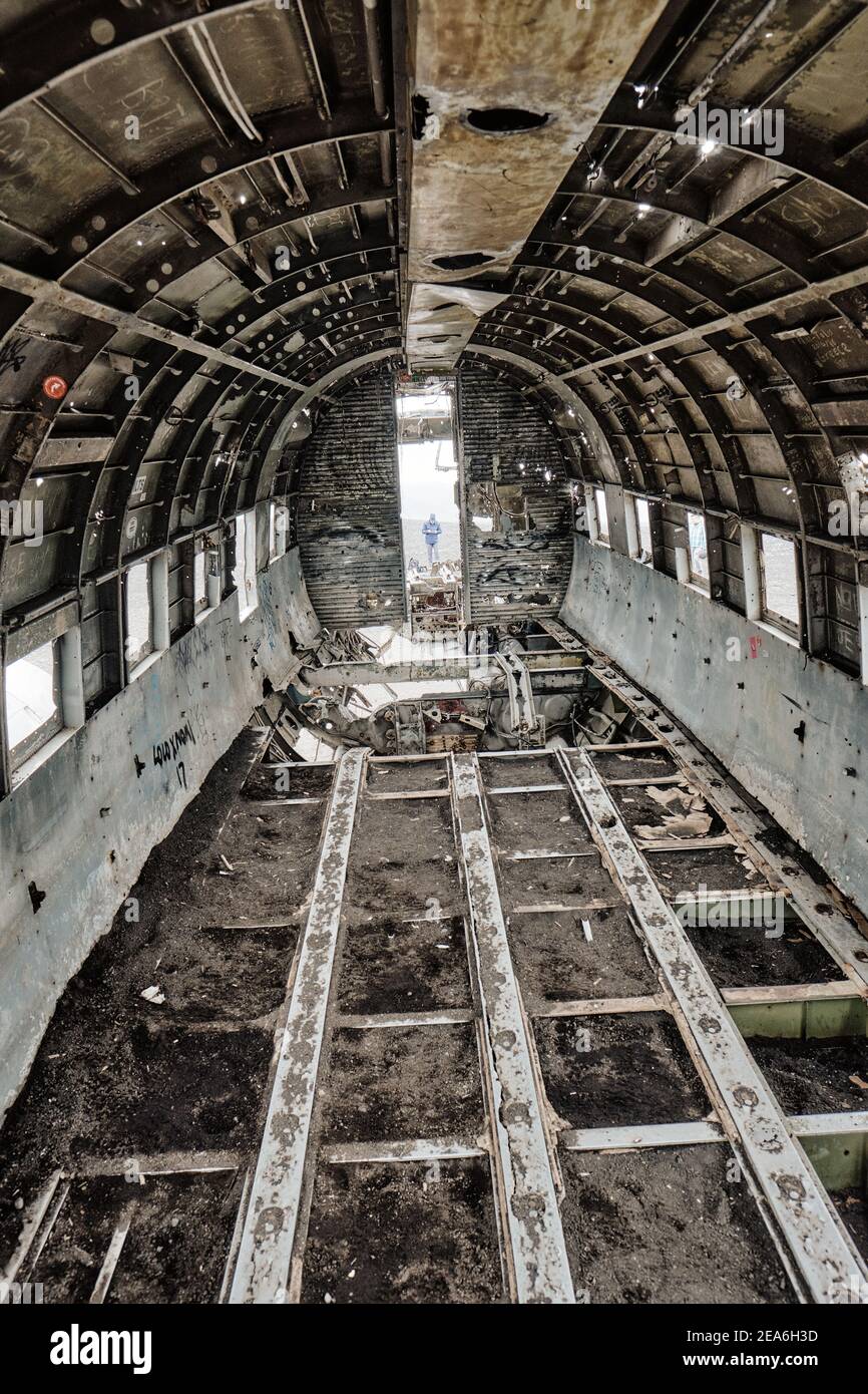 The remote and eerie Dakota plane wreckage fuselage interior in the black sand plain desert of Sólheimasandur in south Iceland. Stock Photo