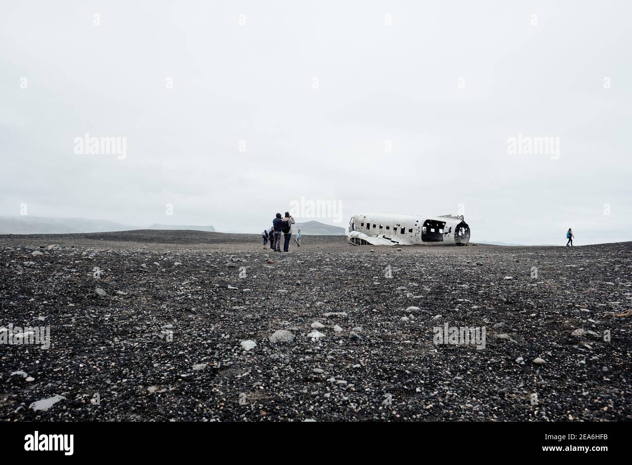 Tourist hikers to the remote and eerie Dakota plane wreckage in the black sand plain desert of Sólheimasandur in south Iceland. Stock Photo