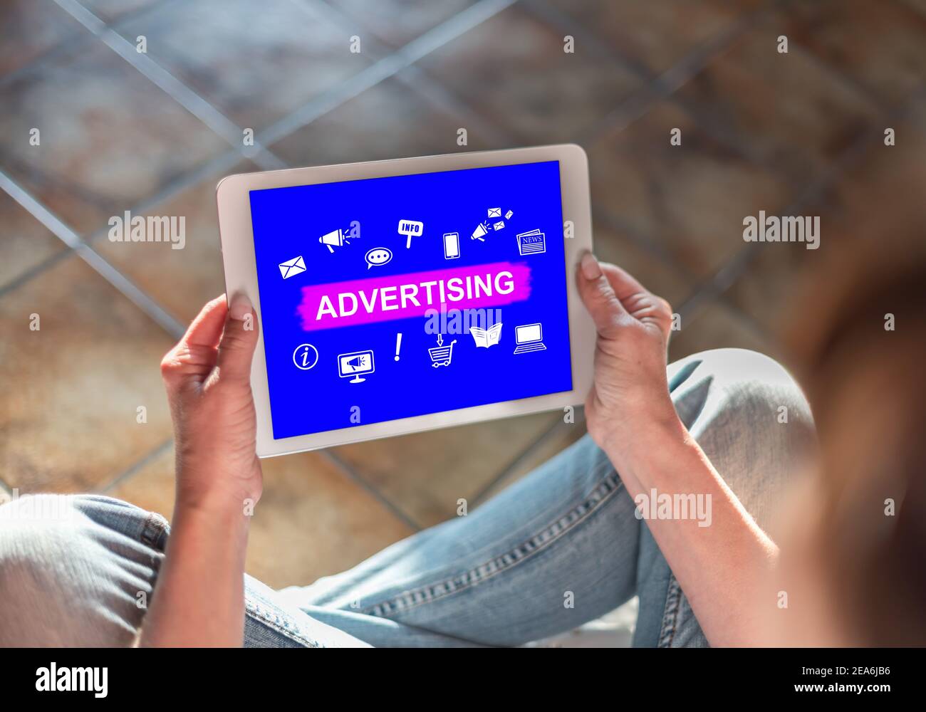Woman sitting on the floor with a tablet showing advertising concept ...