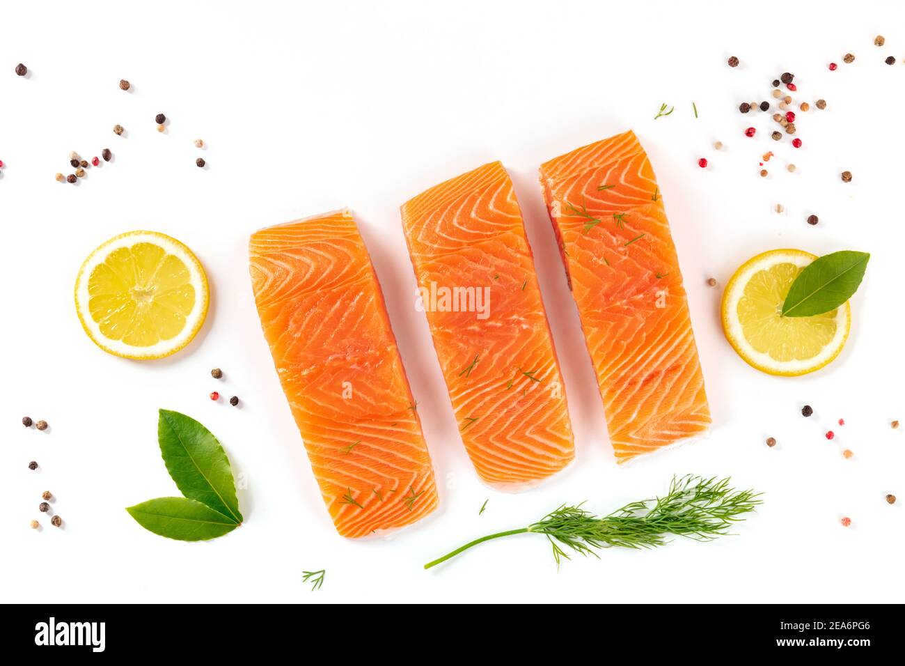 Salmon, overhead flat lay shot with dill, bay leaves, lemon and pepper on a white background