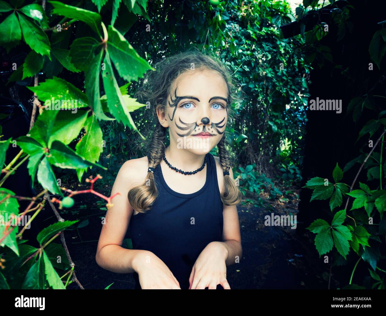 Portrait of a girl with tiger face paint standing in a garden, Italy Stock Photo