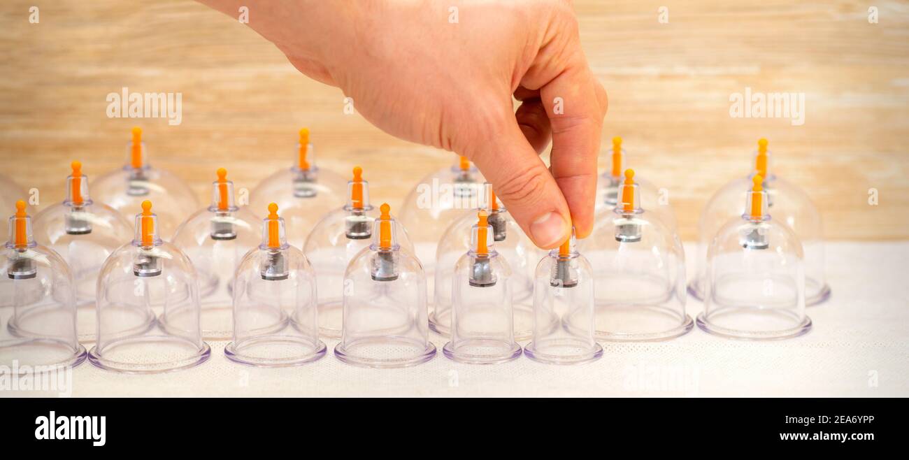 Hand of massage therapist taking vacuum cups from the table before