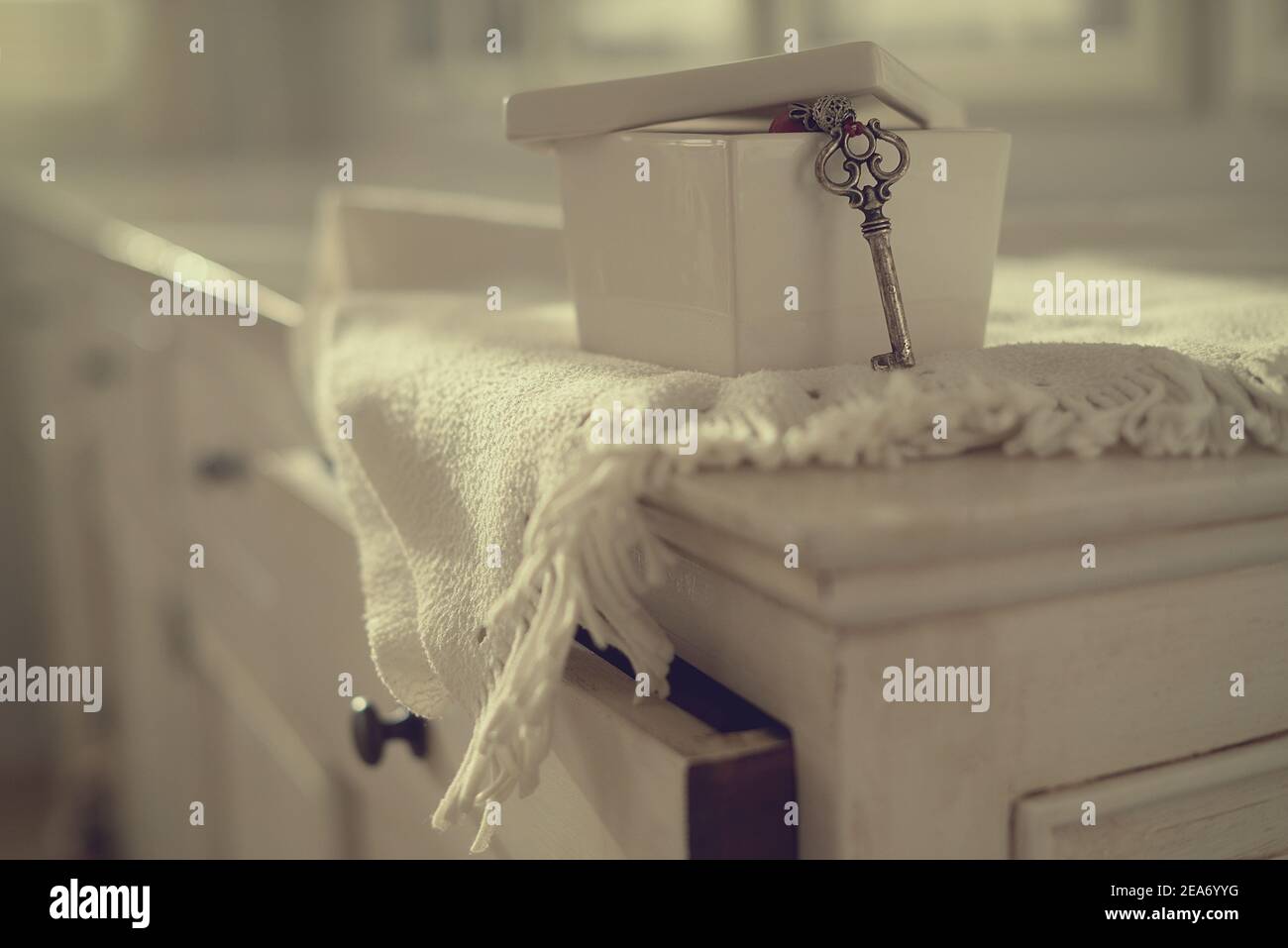 Closeup of a key hanging out of a ceramic box on a chest of drawers