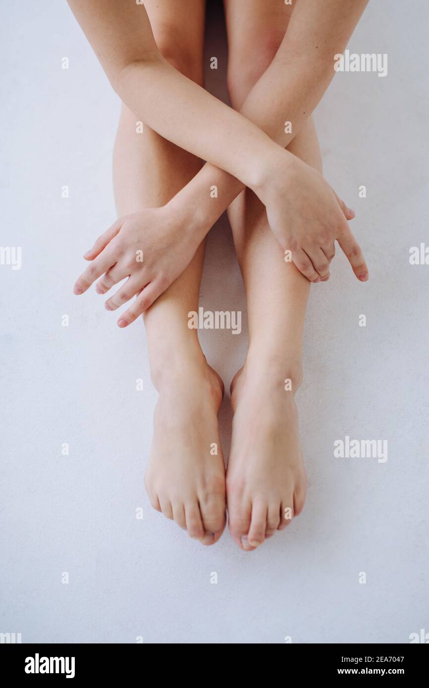 Close-Up of a woman sitting on the floor with her arms folded across her legs Stock Photo