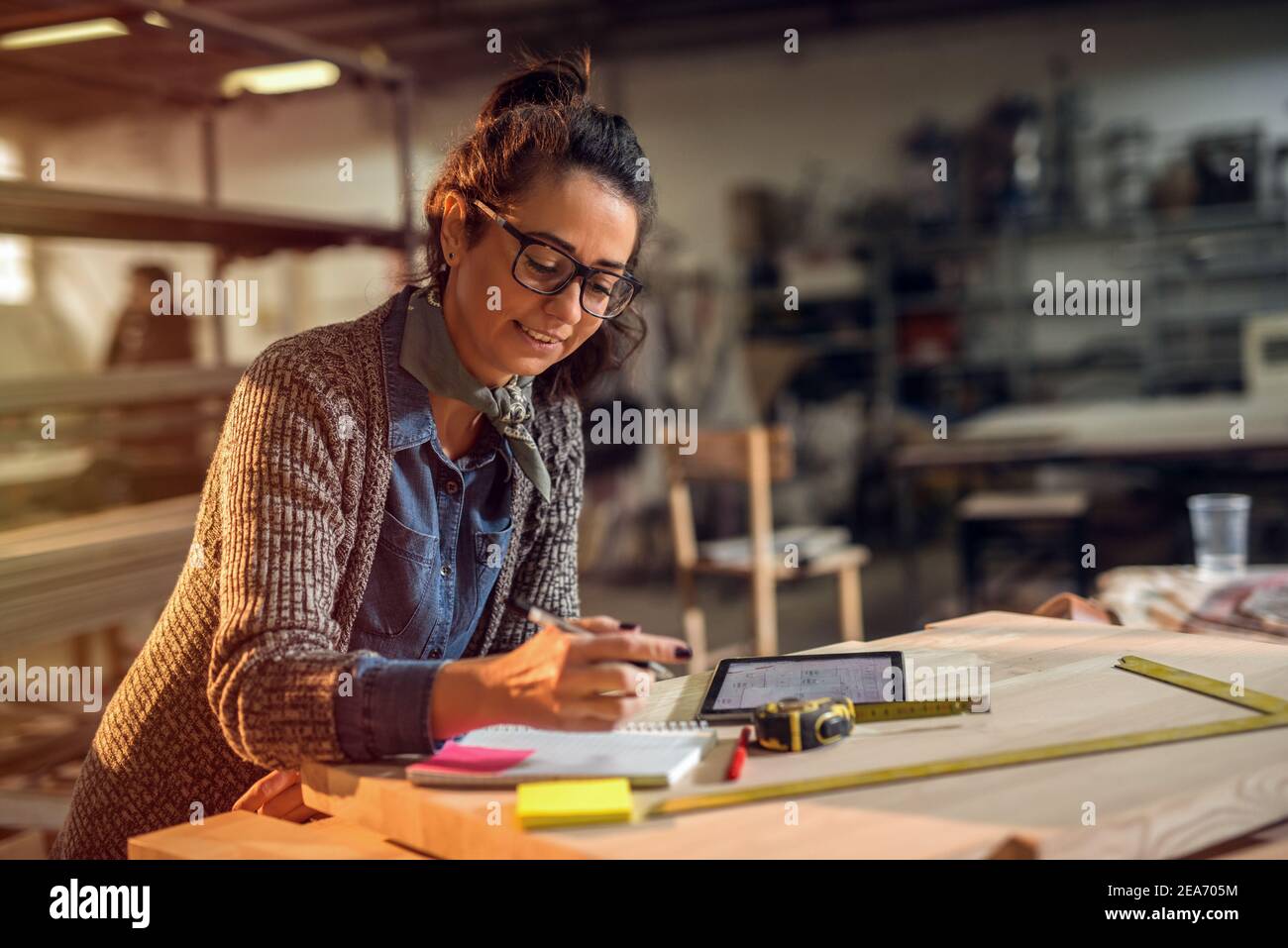 Middle age creative designer in her making studio doing through paper plans. Late night work. Stock Photo