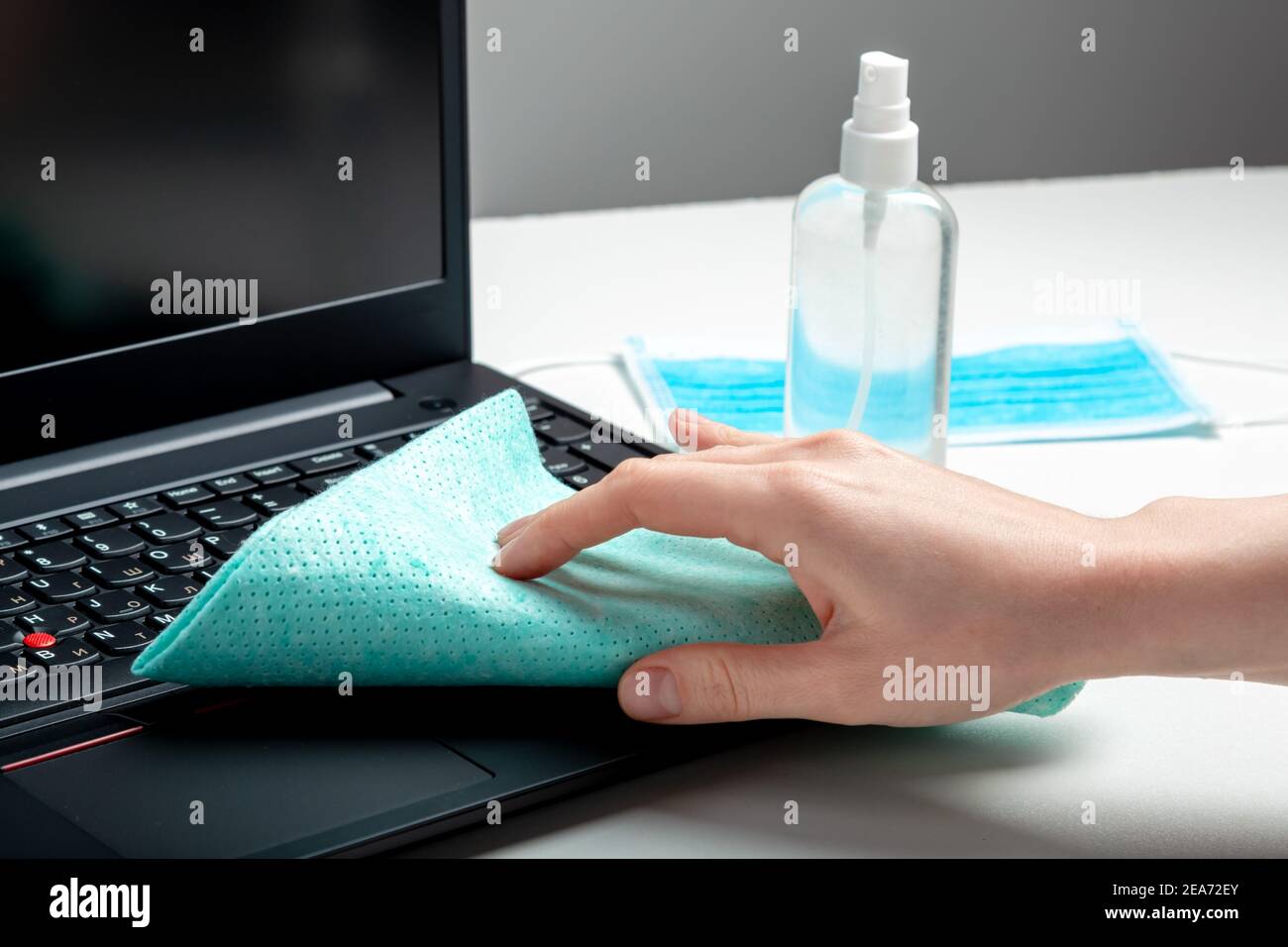 Female hands disinfecting laptop keyboard using Disinfectant spray