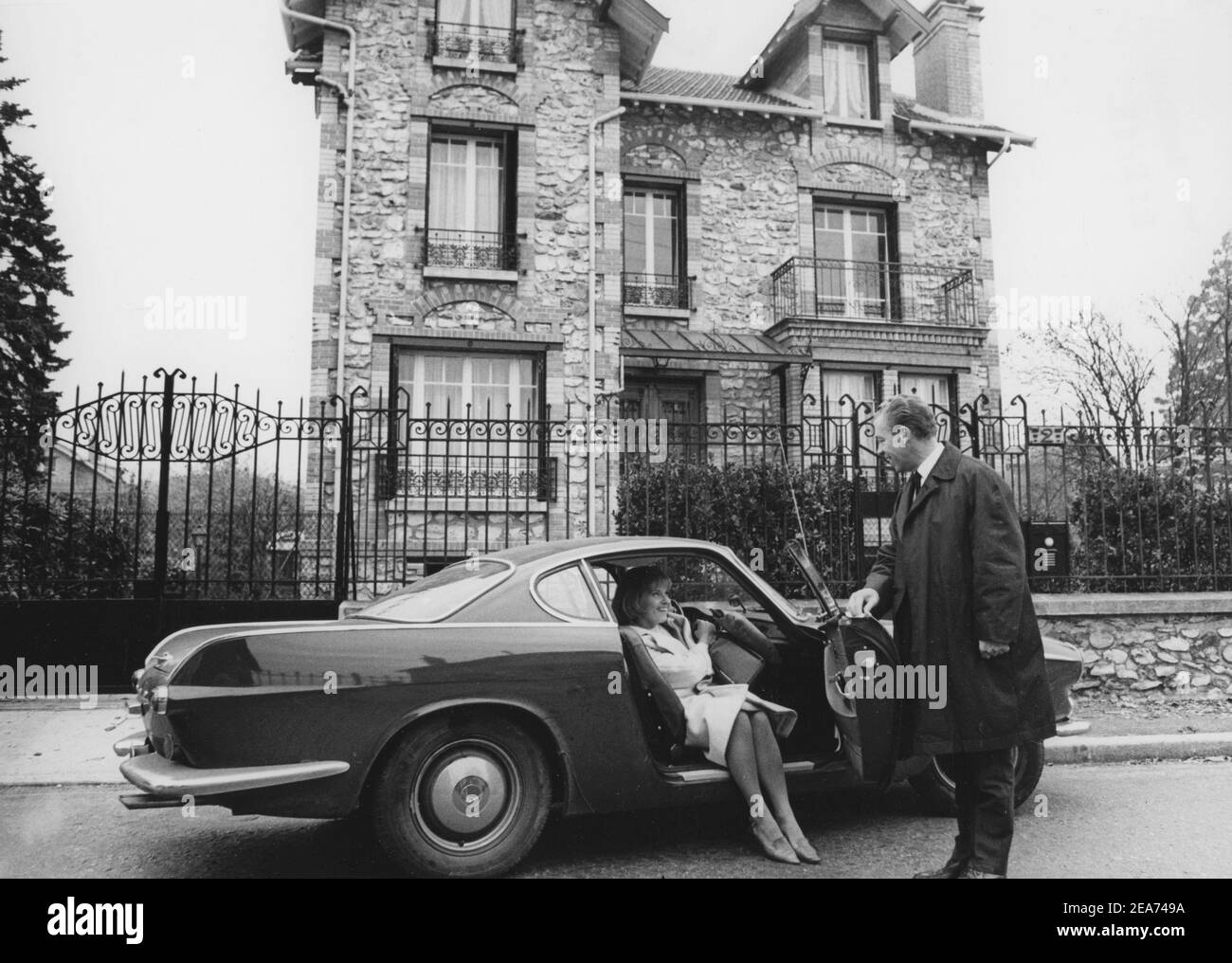Volvo P1800. A sports car manufactured by Volvo Cars wtih start 1961 and ending 1973. Styling was by swedish designer Pelle Pettersson. The car was indroduced at the Geneva Motor Show in 1961.  The P1800  became widely known when driven by then future James Bond actor Roger Moore as Simon Templar in the television series The Saint. Pictured here swedish actress Gunnel Lindblom with her husband outside their villa in France with their Volvo P1800. 1965 Stock Photo