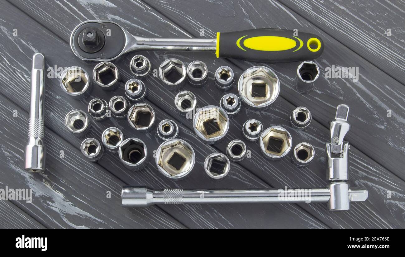 Interchangeable nozzles with a ratchet key on a gray wooden background. Stock Photo