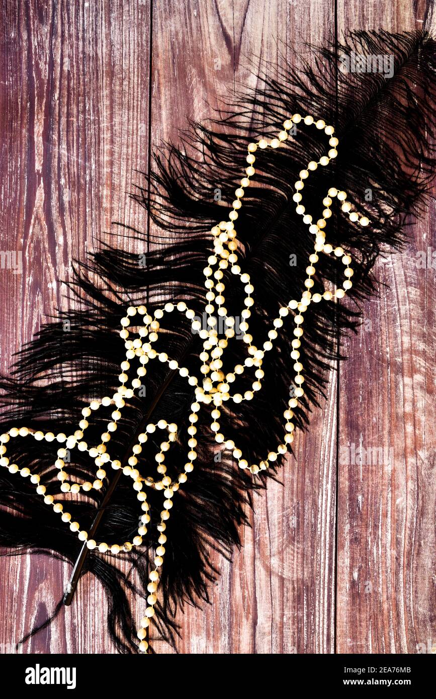 String of pearls and black feather on wood surface Stock Photo