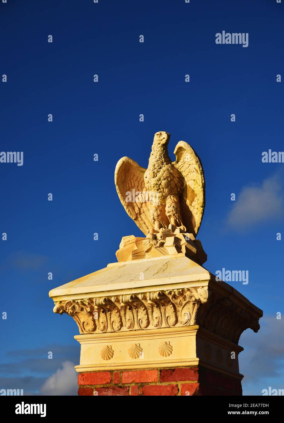Stone eagle on top of a brick pillar against a blue sky, at the entranceto Poole Park, Dorset Stock Photo