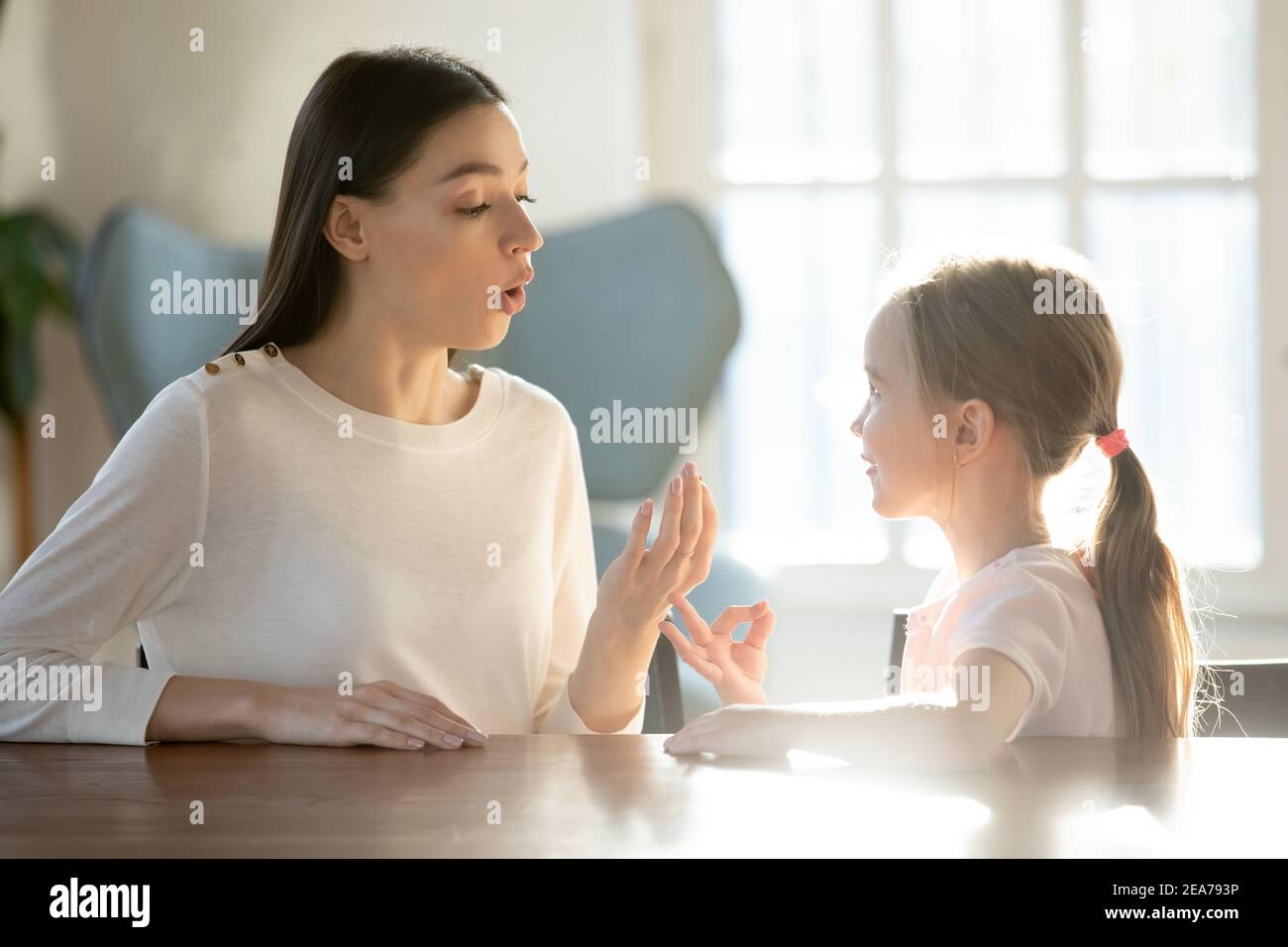 Caring young mom learn pronouncing sounds with daughter Stock Photo