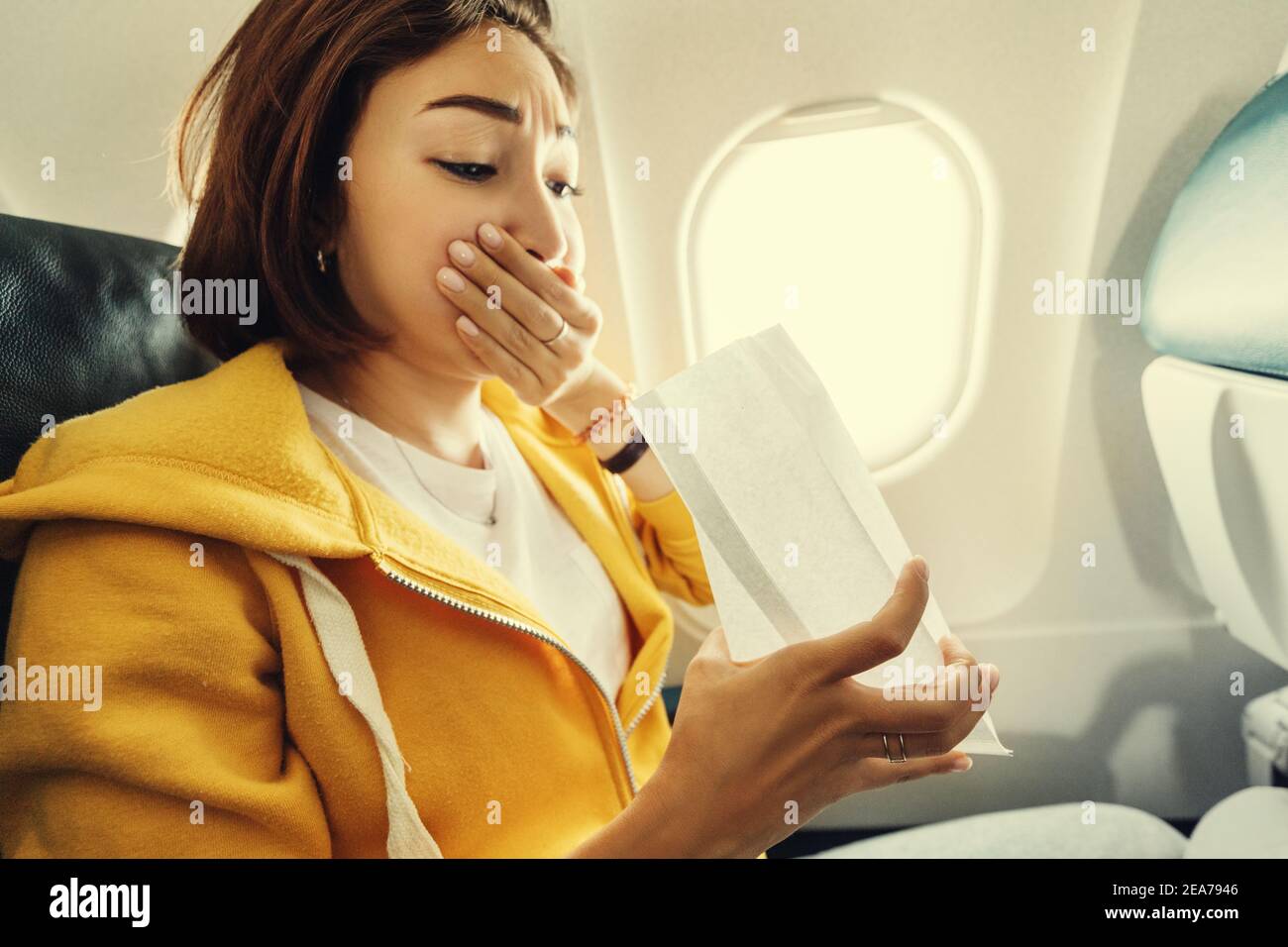 An Asian female traveler suffers from an acute attack of nausea during turbulence on a plane. The woman was seasick and airsock during air flight Stock Photo