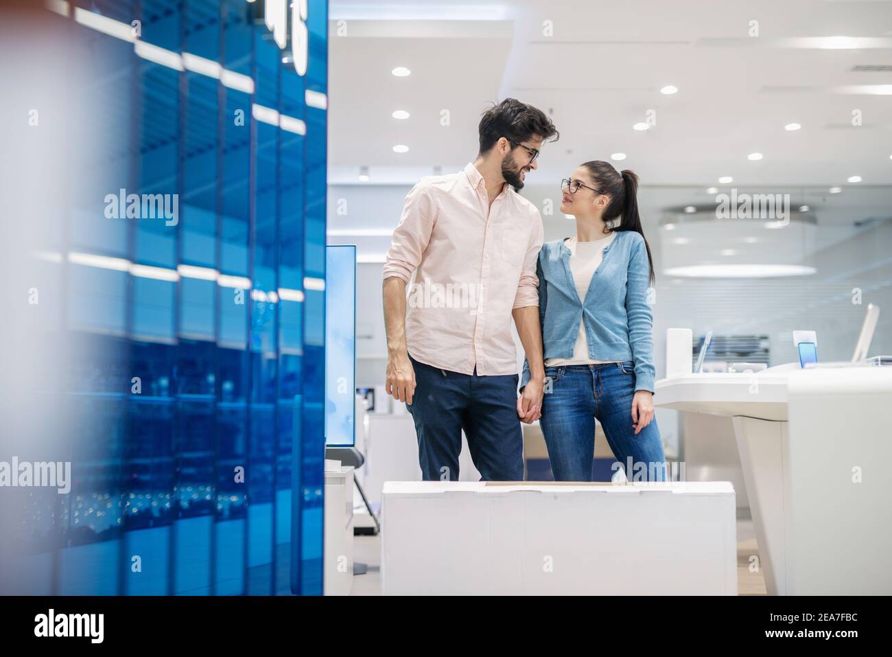 Happy couple buying plasma TV. In front of them packed TV. Stock Photo