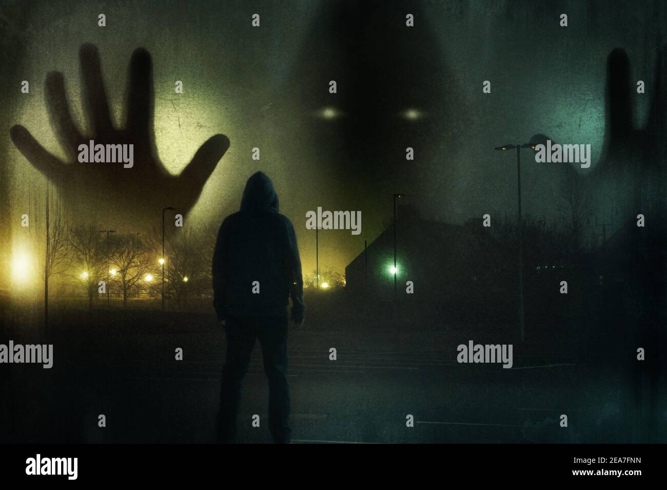 A man looking up at a huge ghostly hooded figure appearing out the mist. On a moody winters night in a city. With a grunge, vintage edit. Stock Photo