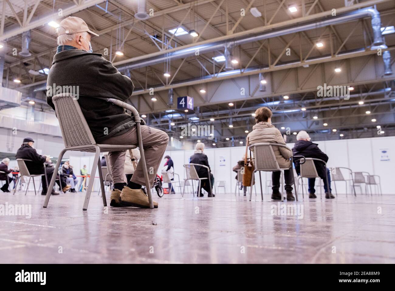 08 February 2021, North Rhine-Westphalia, Essen: People sitting in the waiting area in front of the vaccination lines at the vaccination centre. In North Rhine-Westphalia, all 53 vaccination centres will start operating on 08.02.2021. People living at home from the age of 80 who have previously made a fixed appointment will be vaccinated first. Photo: Rolf Vennenbernd/dpa Stock Photo