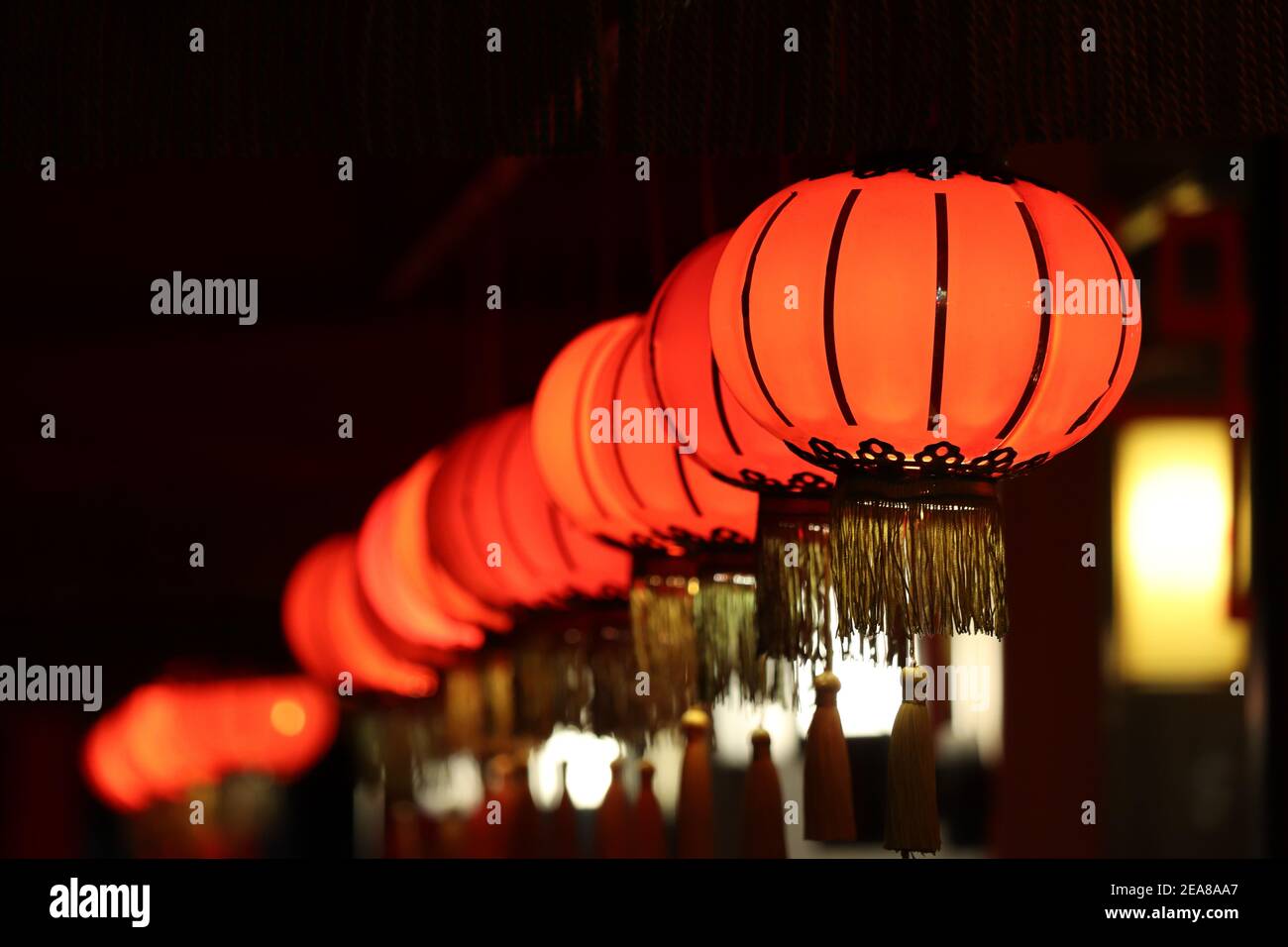 Red Chinese lanterns glow in a row on a night street. New Year celebration in Asia Stock Photo