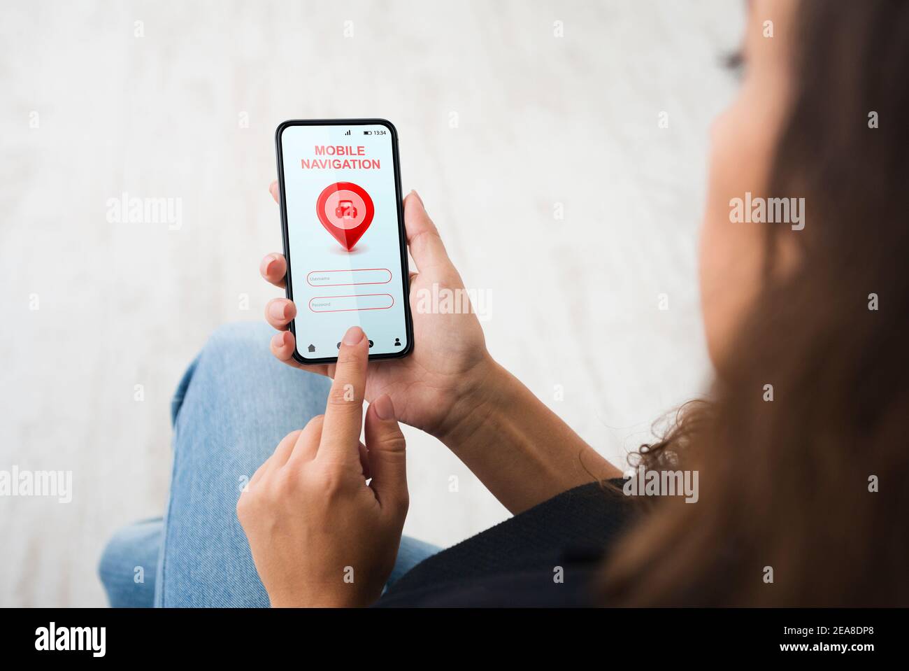 Woman Using Smartphone With Mobile Navigation Application Sitting Indoors Stock Photo