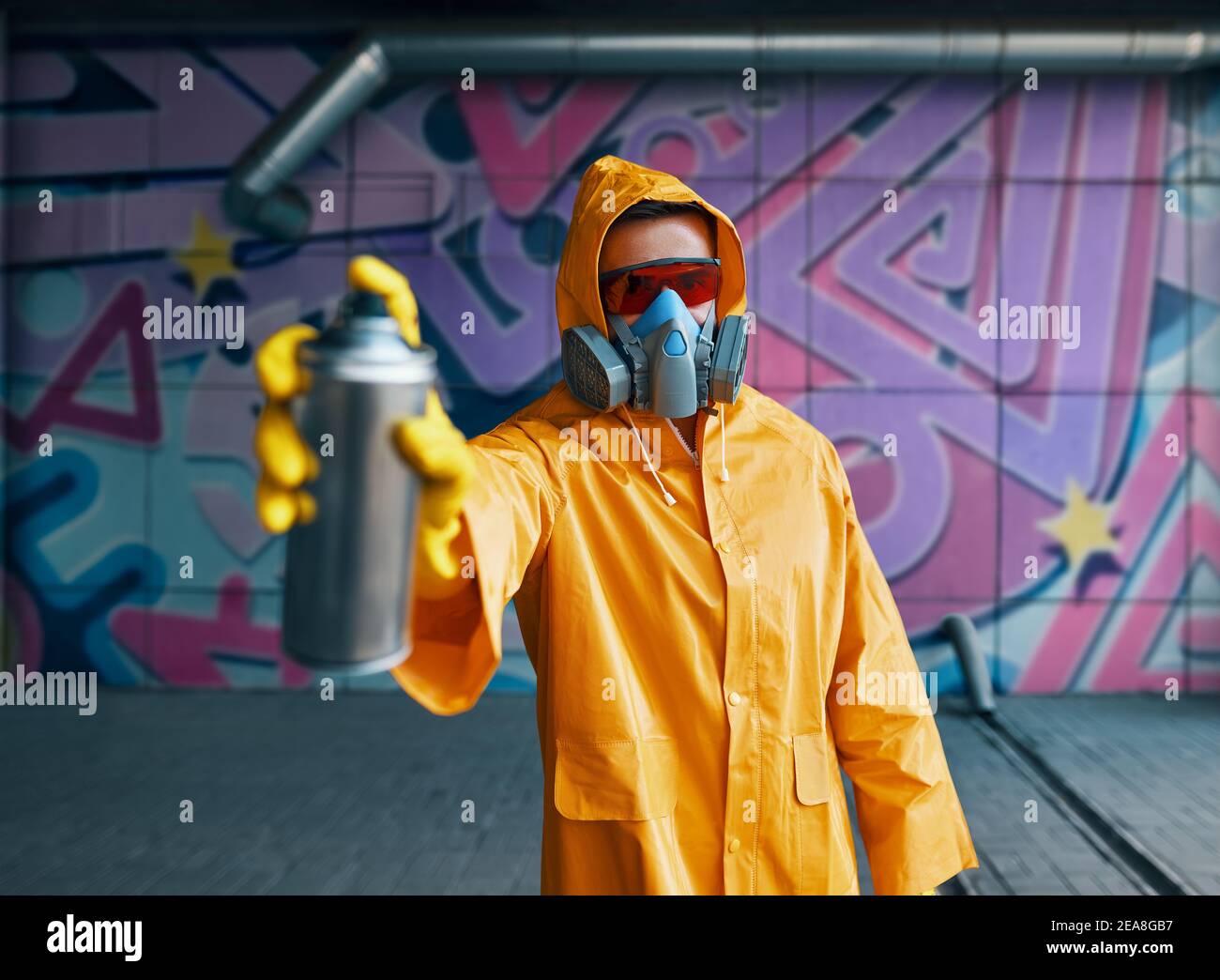 Graffiti artist pointing spray paint can to camera. Urban street modern ...