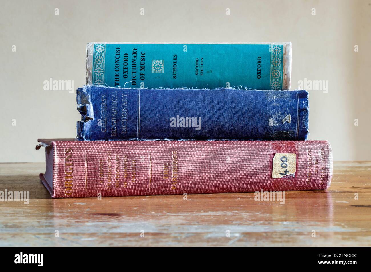 A stack of three old hardback reference books on an old wooden desk Stock Photo
