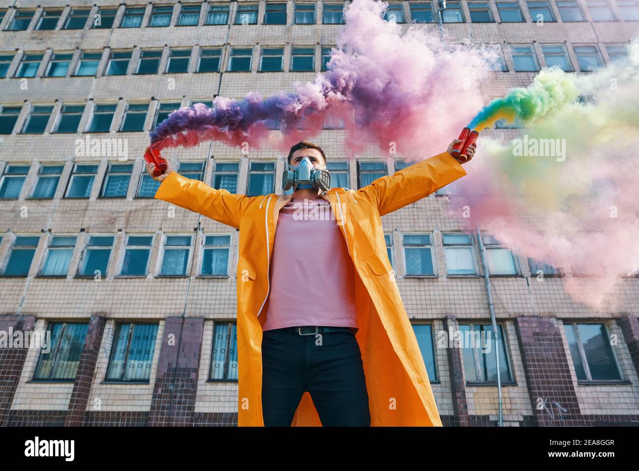 Young man in respirator mask hold smoke bombs in raised hands. protest, freedom, revolution concept Stock Photo